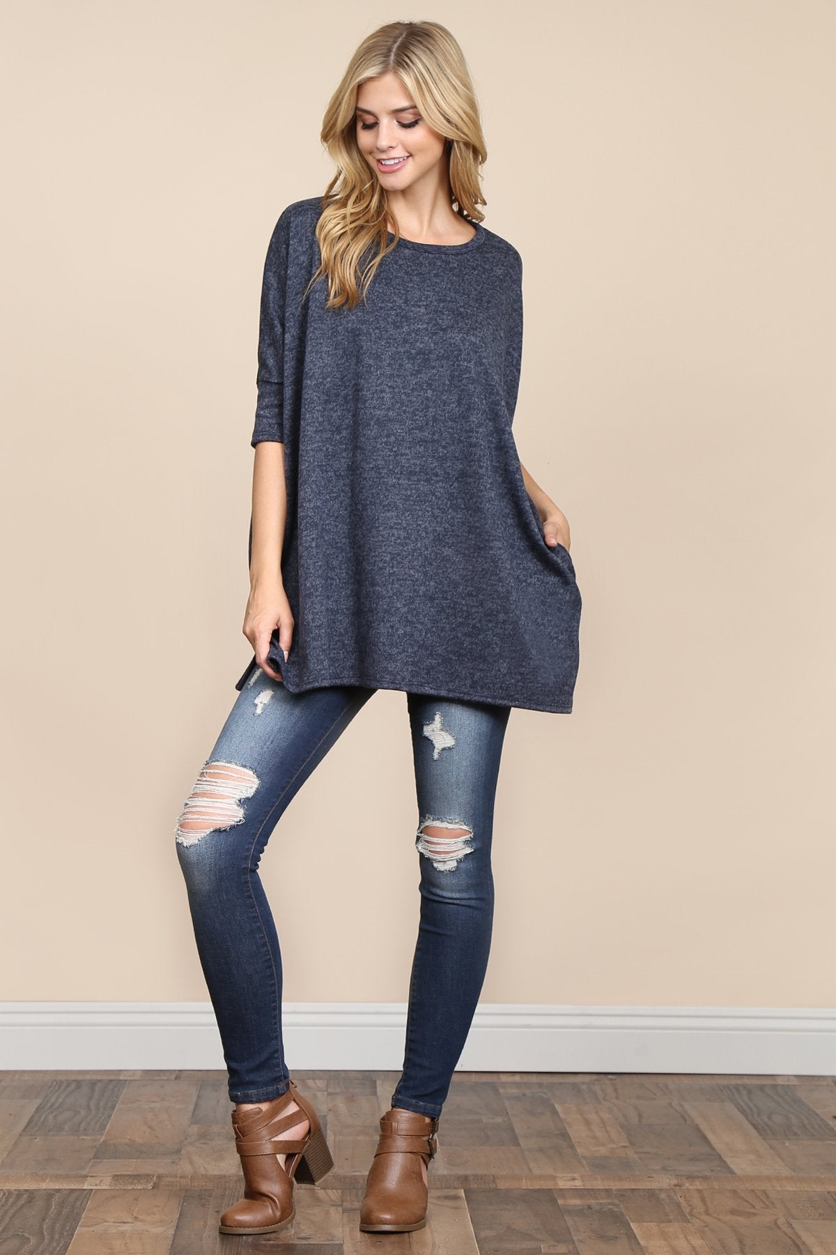 A woman stands against a beige background, wearing Riah Fashions Two Tone Hacci Oversized Dropped Shoulder Pocket Tunic in mustard, with hands in pockets and paired with ripped jeans.