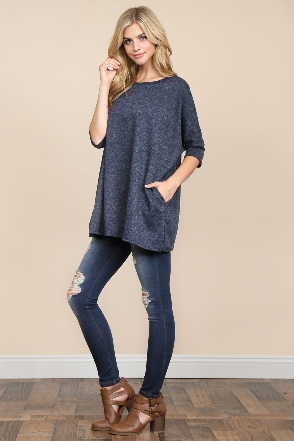 A woman stands against a beige background, wearing Riah Fashions Two Tone Hacci Oversized Dropped Shoulder Pocket Tunic in mustard, with hands in pockets and paired with ripped jeans.