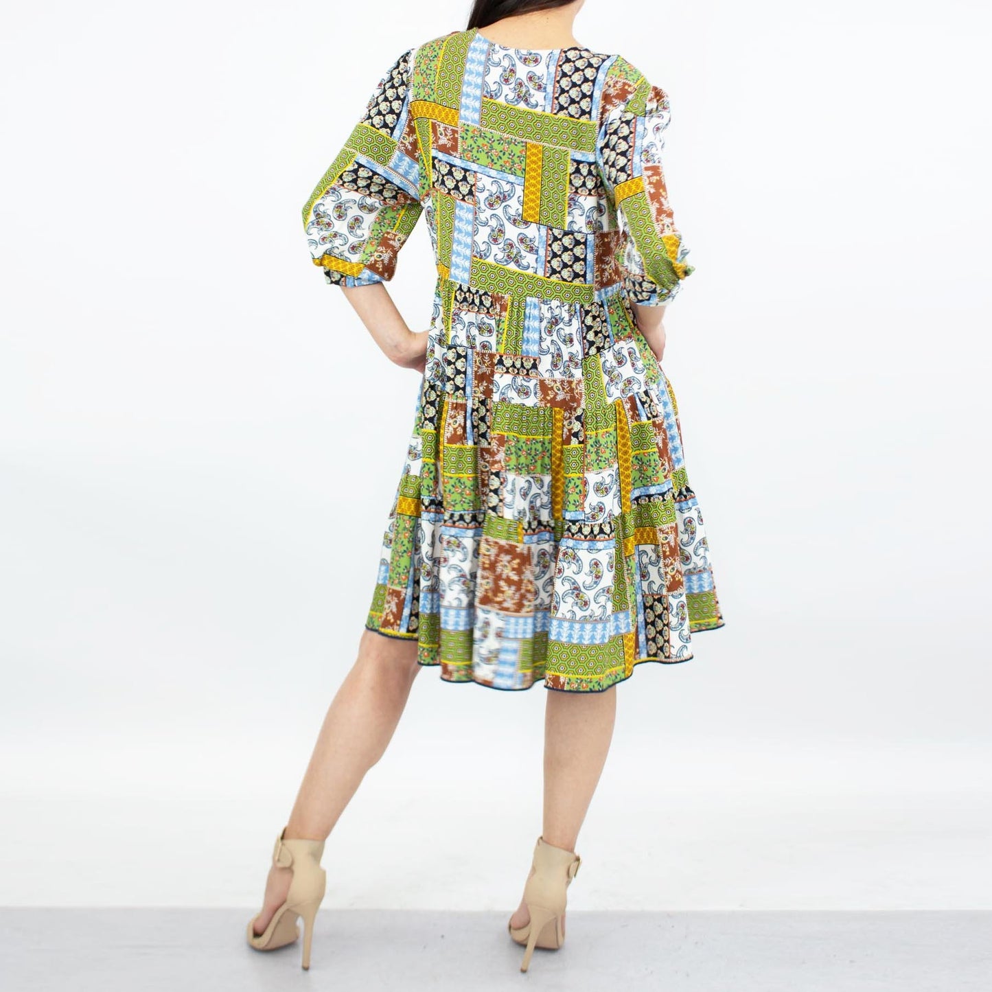 Person wearing a Stylespect Flare Bottom 3/4 Sleeve Dress in green, paired with beige heels, posing against a plain background.
