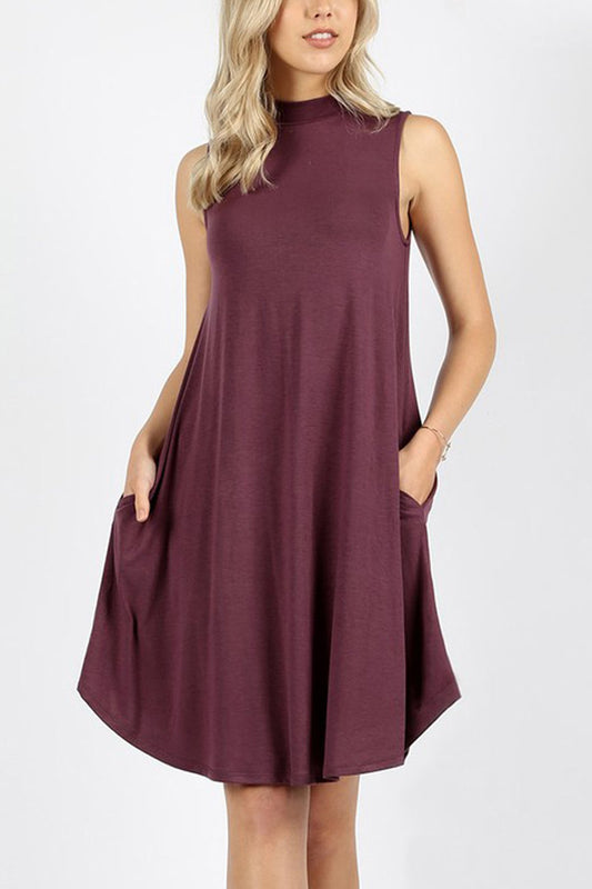 A woman is wearing the Riah Fashion Premium Mock Neck Sleeveless Dress with pockets in maroon, with her right hand in a pocket.