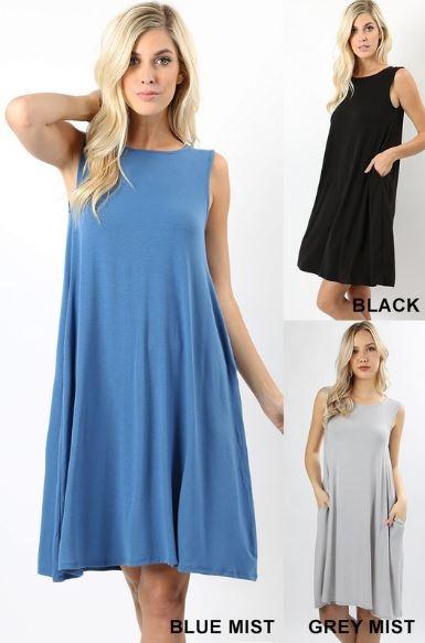 A person with long, light-colored hair wears a Sleeveless Flared Pocket Dress in light green by Riah Fashion outside, holding the dresss sides along with a triangular pendant necklace.