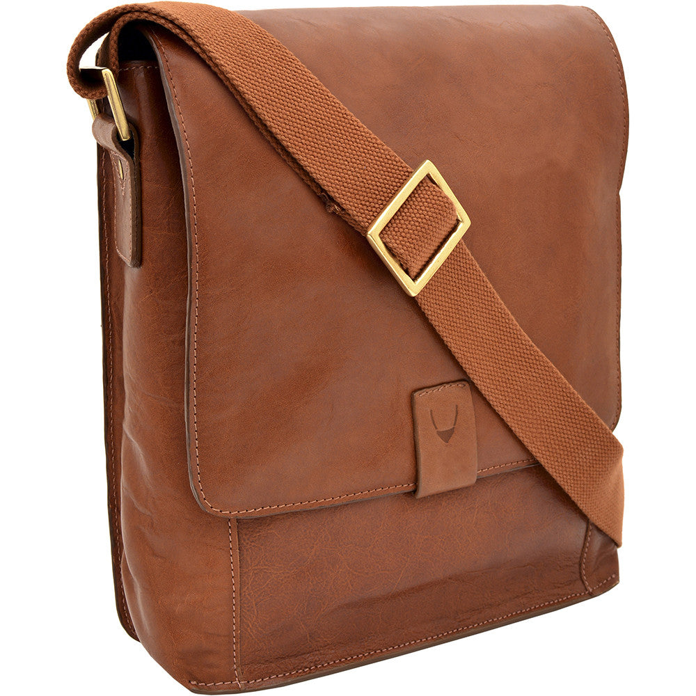 The Aiden Genuine Leather Mini Crossbody by Hidesign is a brown leather shoulder bag featuring a flap cover and an adjustable fabric strap with a brass buckle.