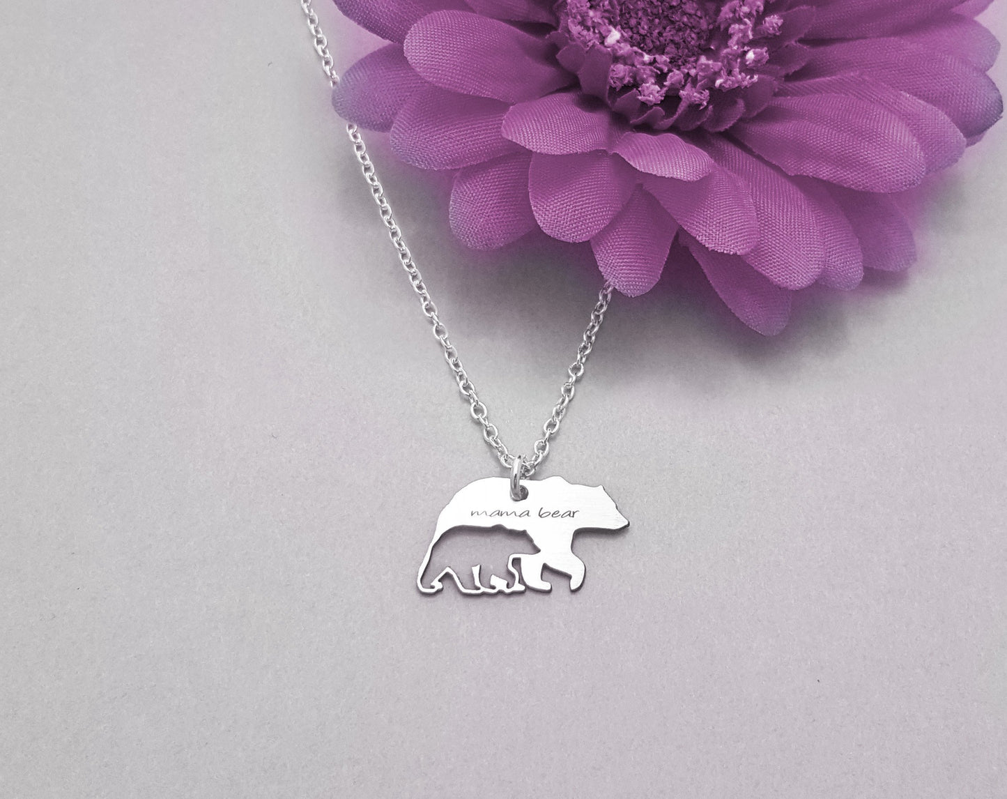 The Mama Bear and Cub Necklace by Sincerely Silver is a silver piece with a bear-shaped pendant featuring three cubs and inscribed with mama bear.