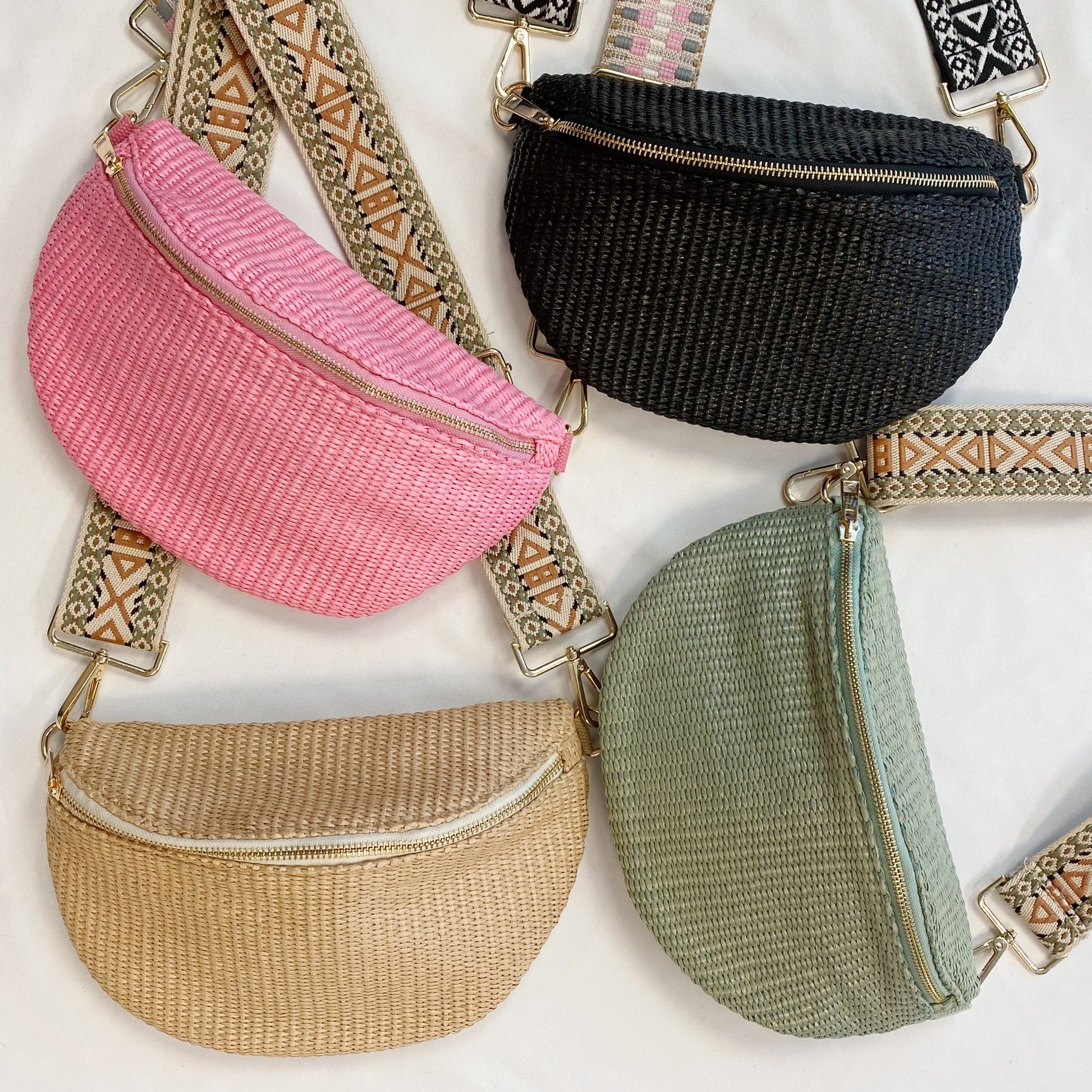 Four Bahama Breeze Fit All Sling Bags by Ellison + Young in pink, black, beige, and green with unique patterned straps are displayed on a white surface.