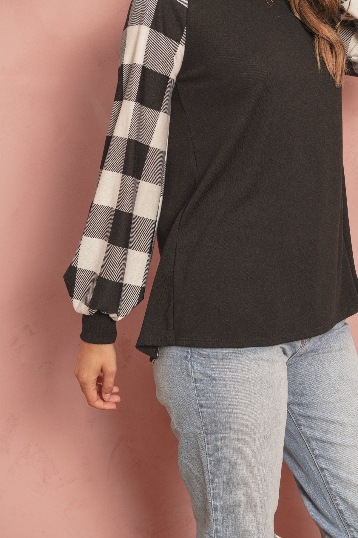 A woman wearing a faded denim plaid puff sleeved round neck top by Riah Fashion and ripped jeans stands against a plain background.