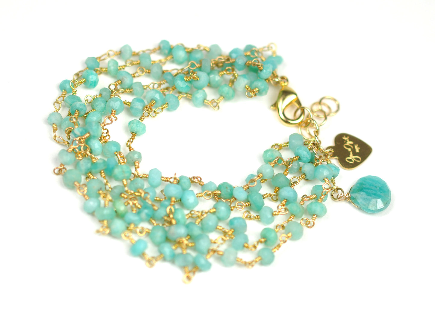 The Amazonite Bracelet by Gena Myint is a multi-strand piece featuring turquoise beads, a gold chain, a heart-shaped charm, and a clasp.