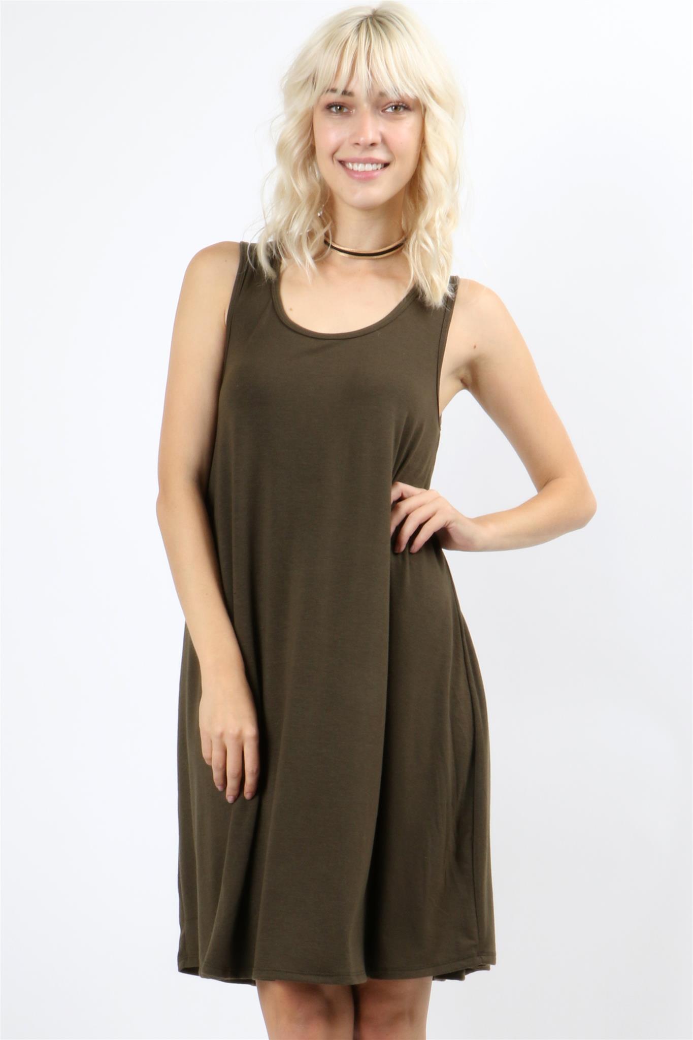 A person with long, light-colored hair wears a Sleeveless Flared Pocket Dress in light green by Riah Fashion outside, holding the dresss sides along with a triangular pendant necklace.