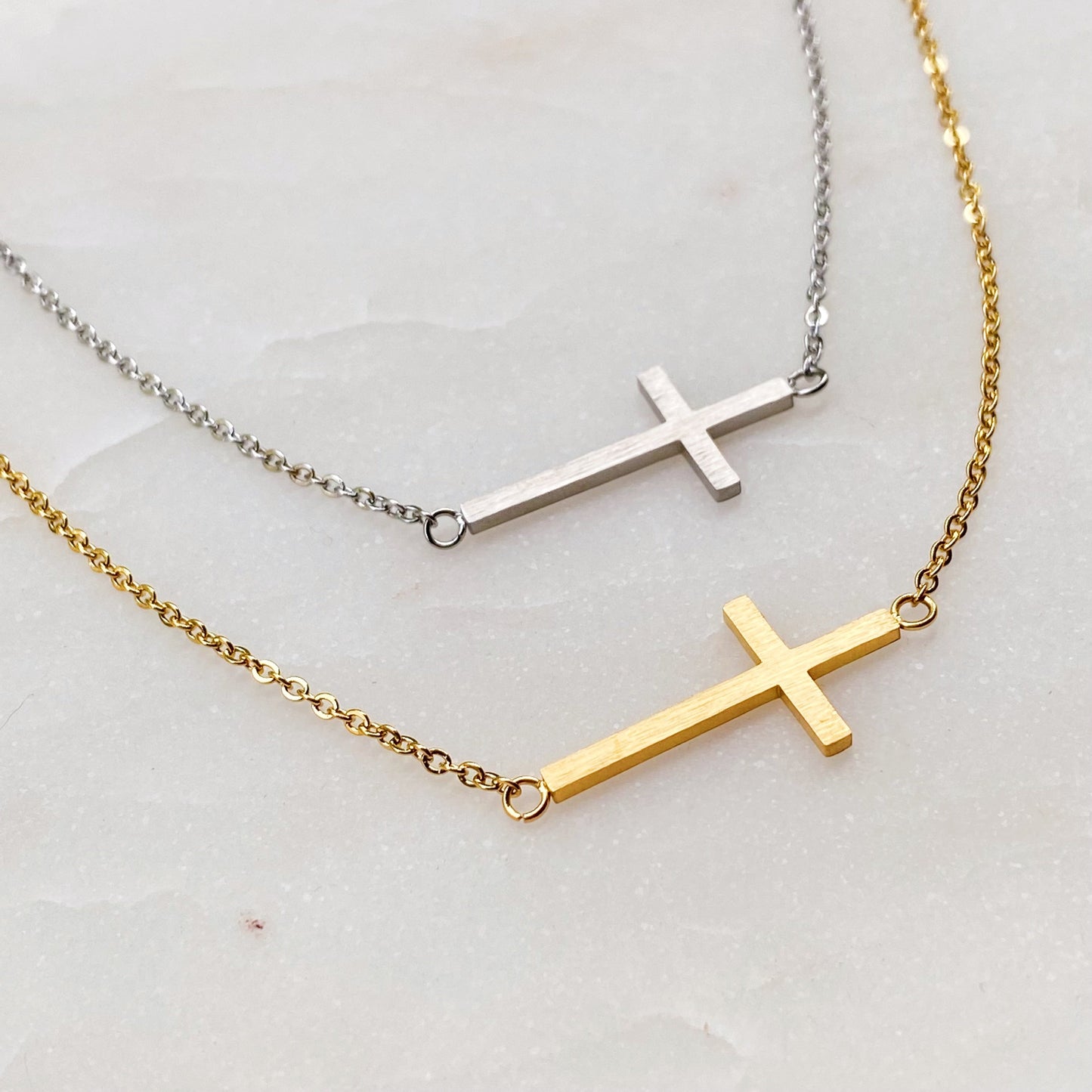 Two Kayla Cross Necklaces from Ellison + Young, one silver and one gold, presented on a white surface.