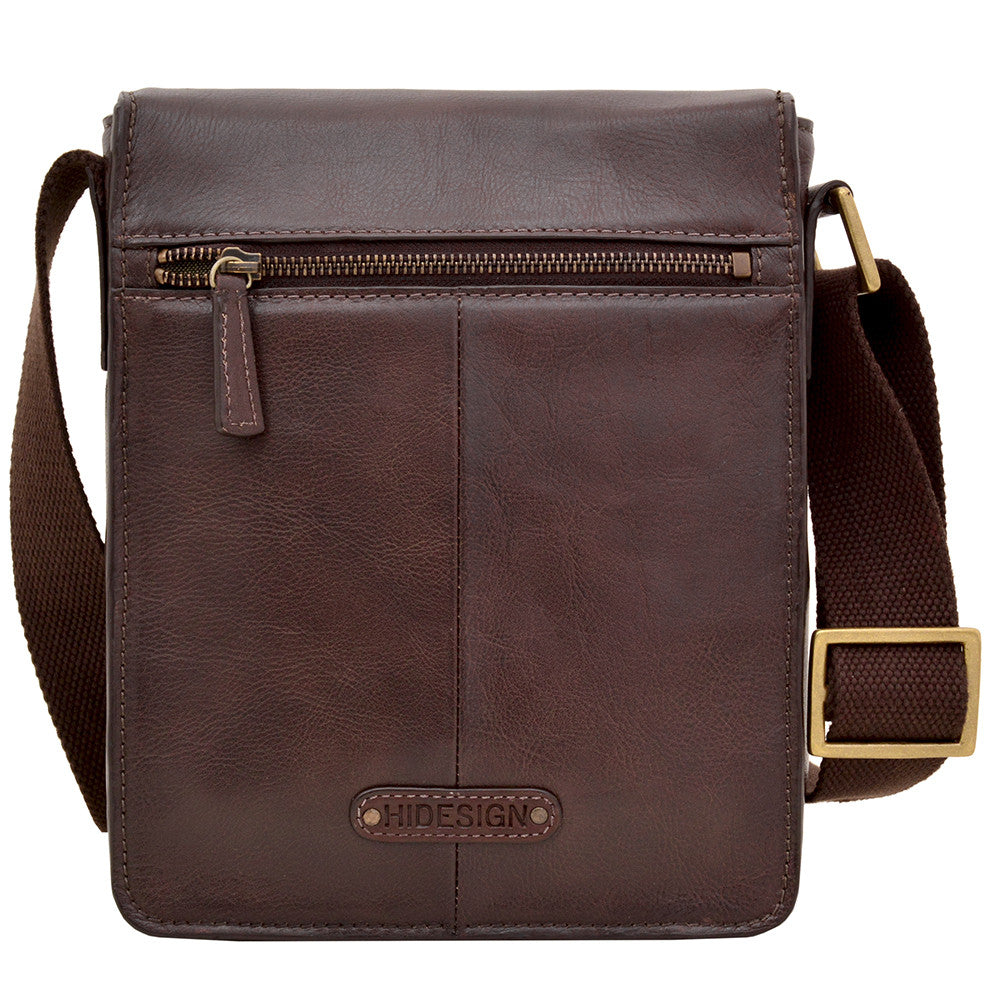 The Aiden Genuine Leather Mini Crossbody by Hidesign is a brown leather shoulder bag featuring a flap cover and an adjustable fabric strap with a brass buckle.