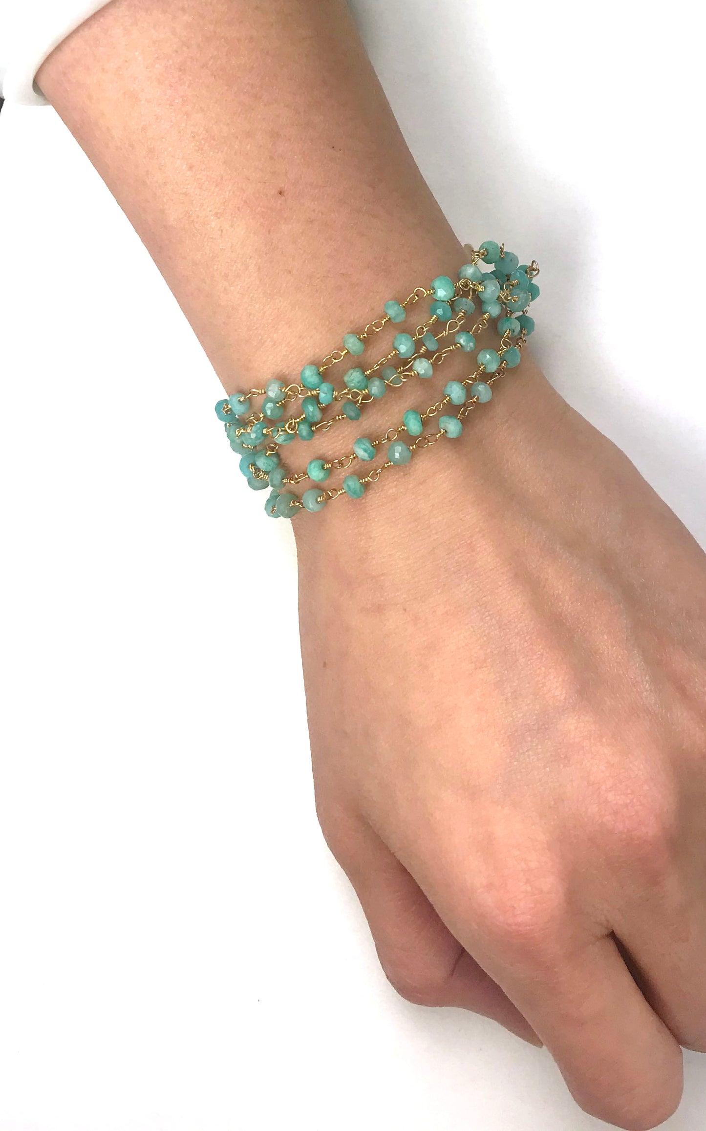 The Amazonite Bracelet by Gena Myint is a multi-strand piece featuring turquoise beads, a gold chain, a heart-shaped charm, and a clasp.