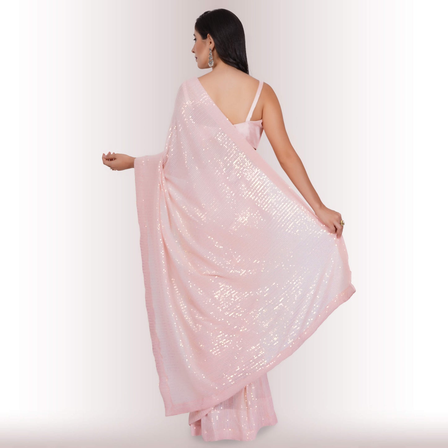 A person wearing Chiros Ready Made Sequin Saree in Blush poses with one hand on their hip against a light background.