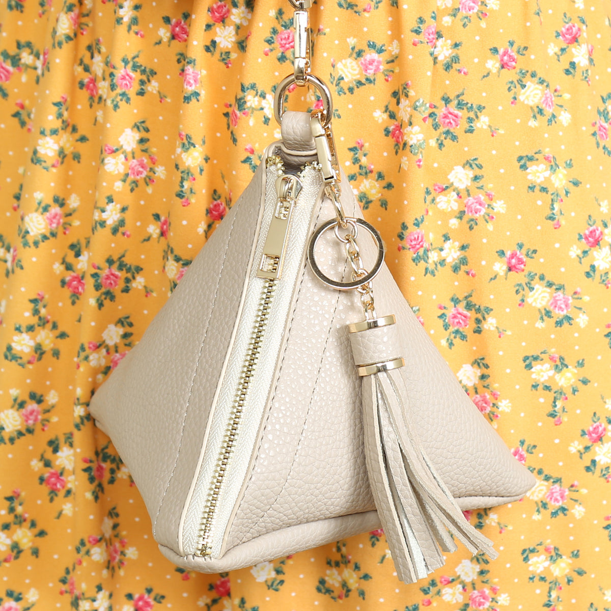 A person in a white shirt and jeans is holding the Riah Fashion Pyramid Shape Tassel Wristlet Leather Bag in orange.