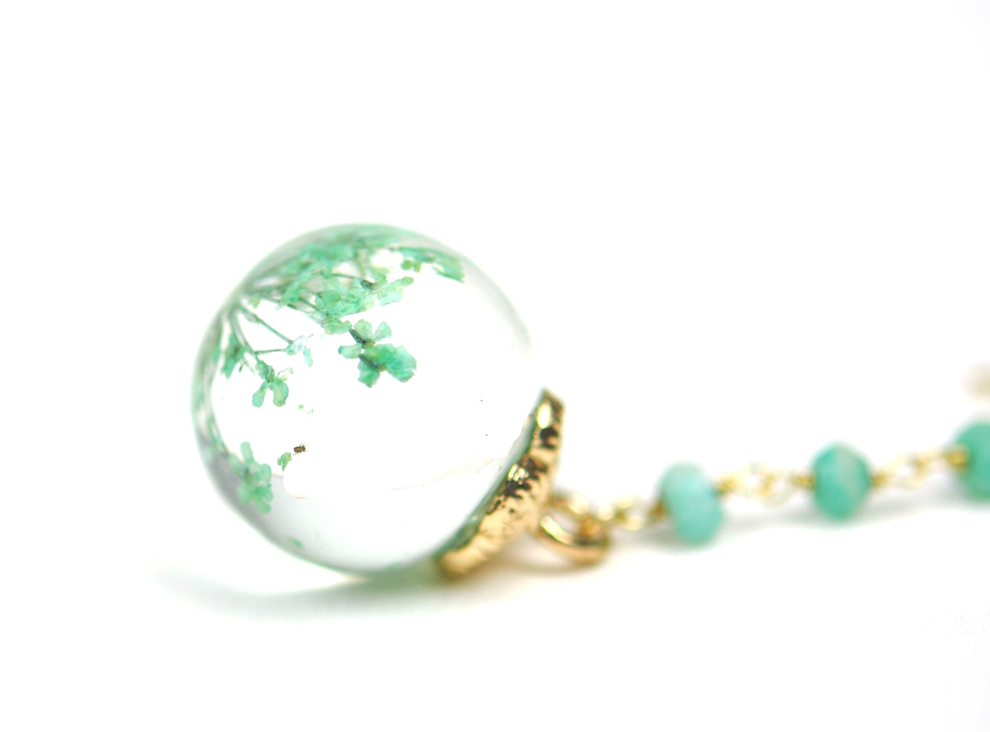Gena Myints Petrified Flower Keepsake Amazonite Earrings feature dangling earrings with green beads and round spheres showcasing small plant-like designs.