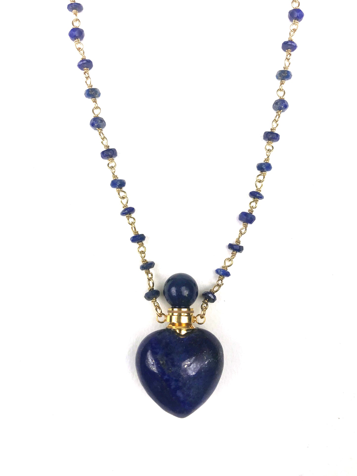The Gena Myint Lapis Lazuli Heart Necklace features a blue beaded design with a heart-shaped pendant and gold chain clasp.