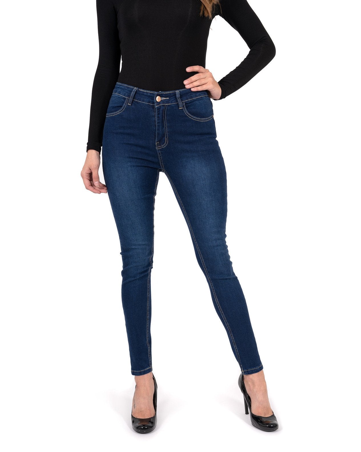 A person stands by a pool wearing a black long-sleeve shirt, Alexis High Waist Skinny Jeans by Savoy Active, and heels. Tall trees and vibrant flowers surround the area.
