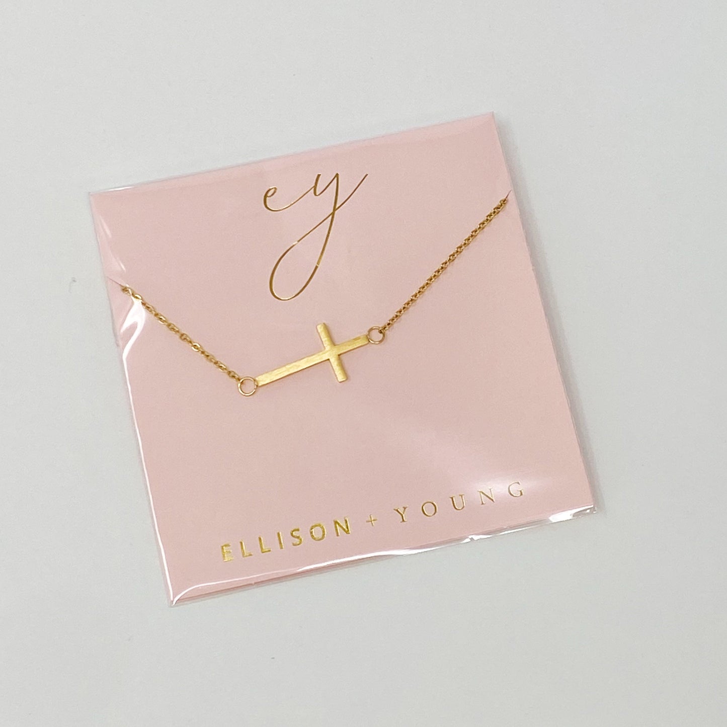Two Kayla Cross Necklaces from Ellison + Young, one silver and one gold, presented on a white surface.