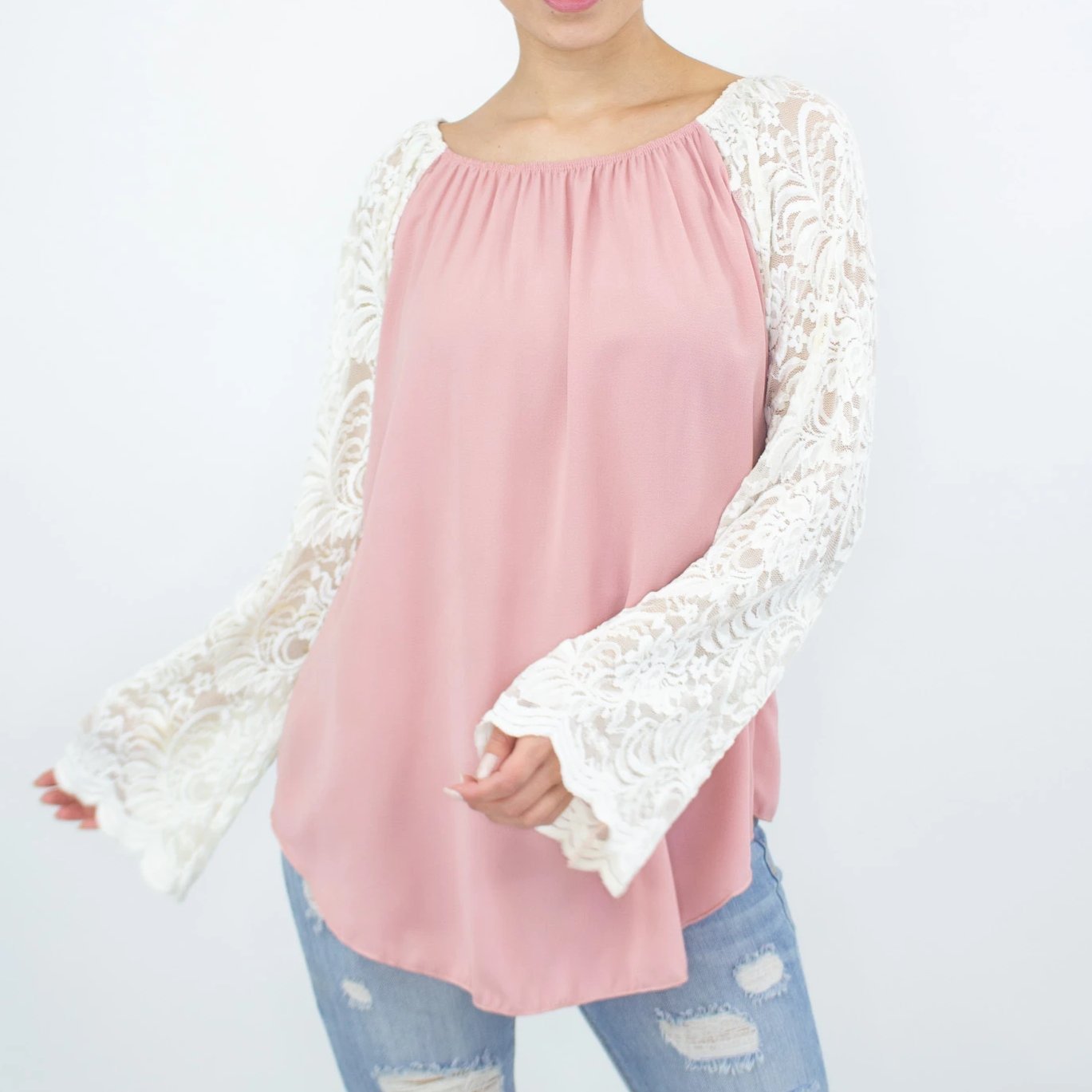 A person in a Stylespect Lace Sleeve Backless Top - Rose with ripped jeans stands against a plain background.