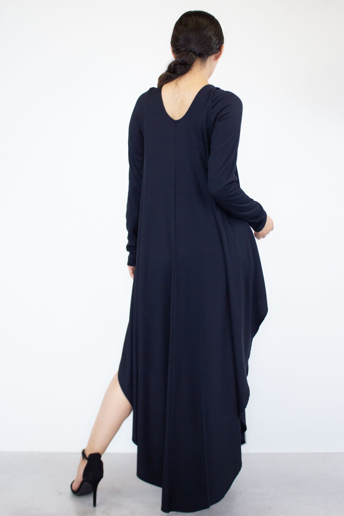 A person is wearing the Stylespect Asymmetric Long Sleeve Maxi Dress and high heels, standing against a plain white background.