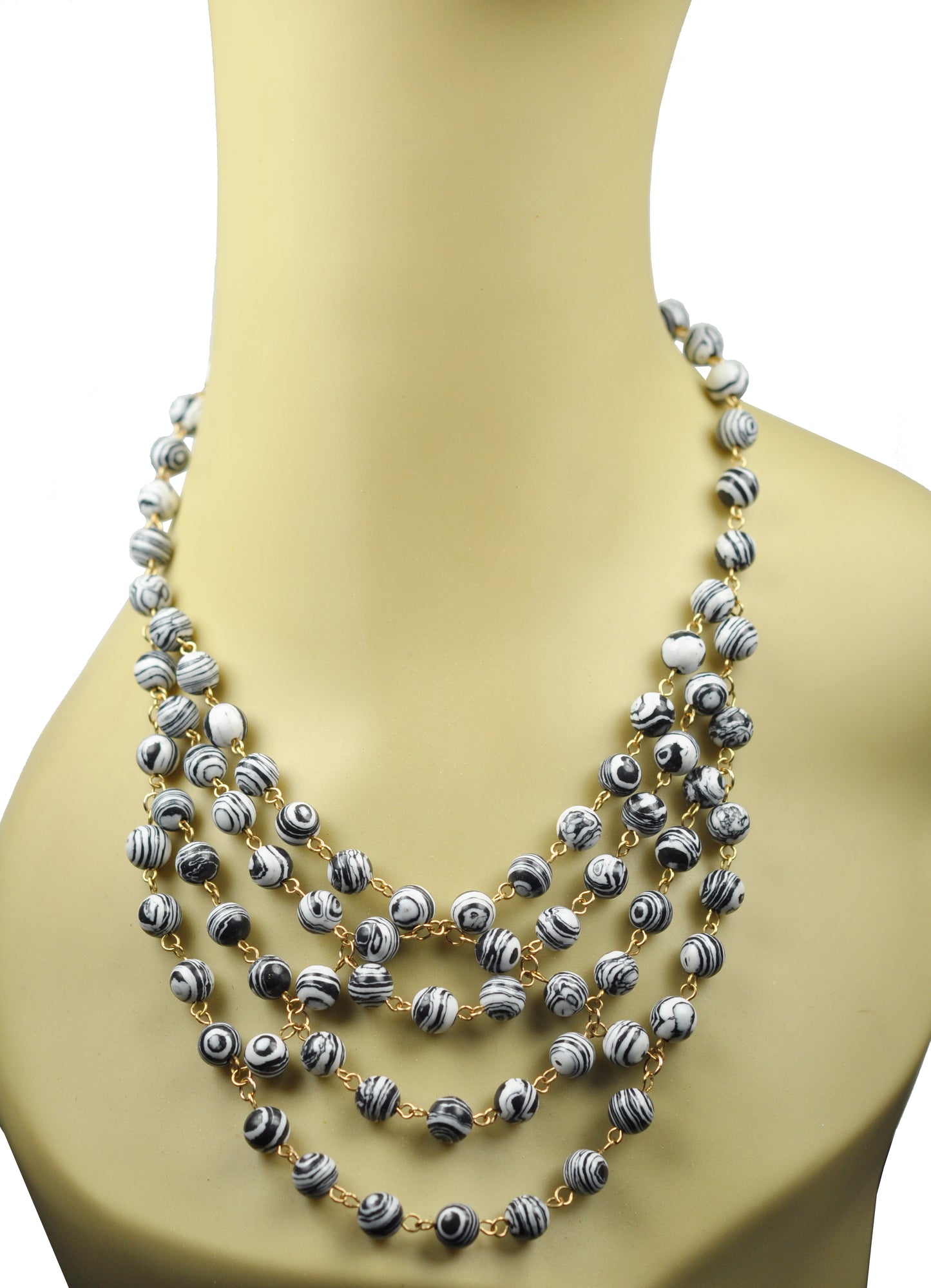 The Gena Myint Zebra Stripe Turquoise Statement Necklace features multi-strand black and white swirled beads with gold links, displayed on a white background.