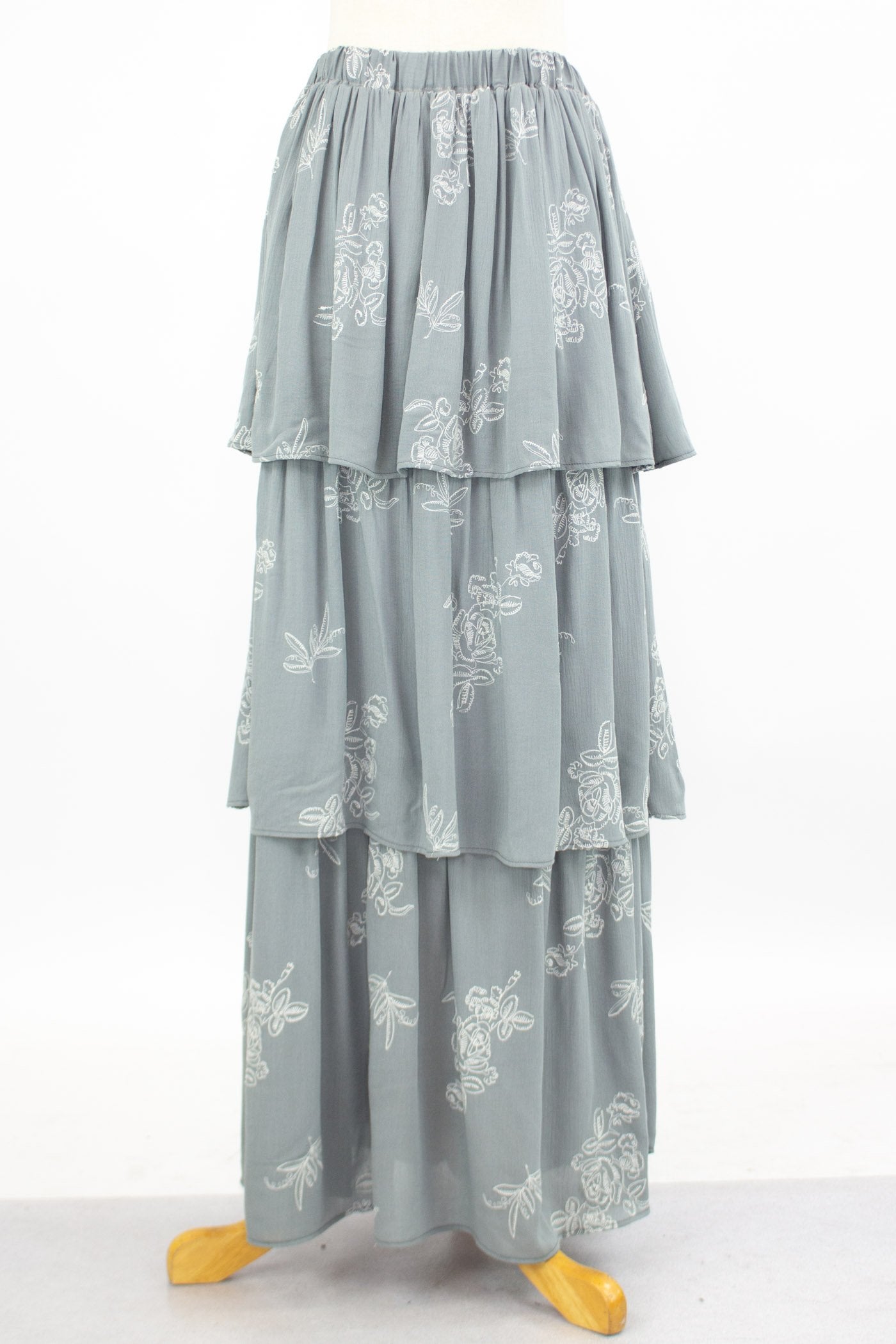 The mannequin displays the Stylespect Layered Ruffle Maxi Skirt in light gray, featuring white floral embroidery.