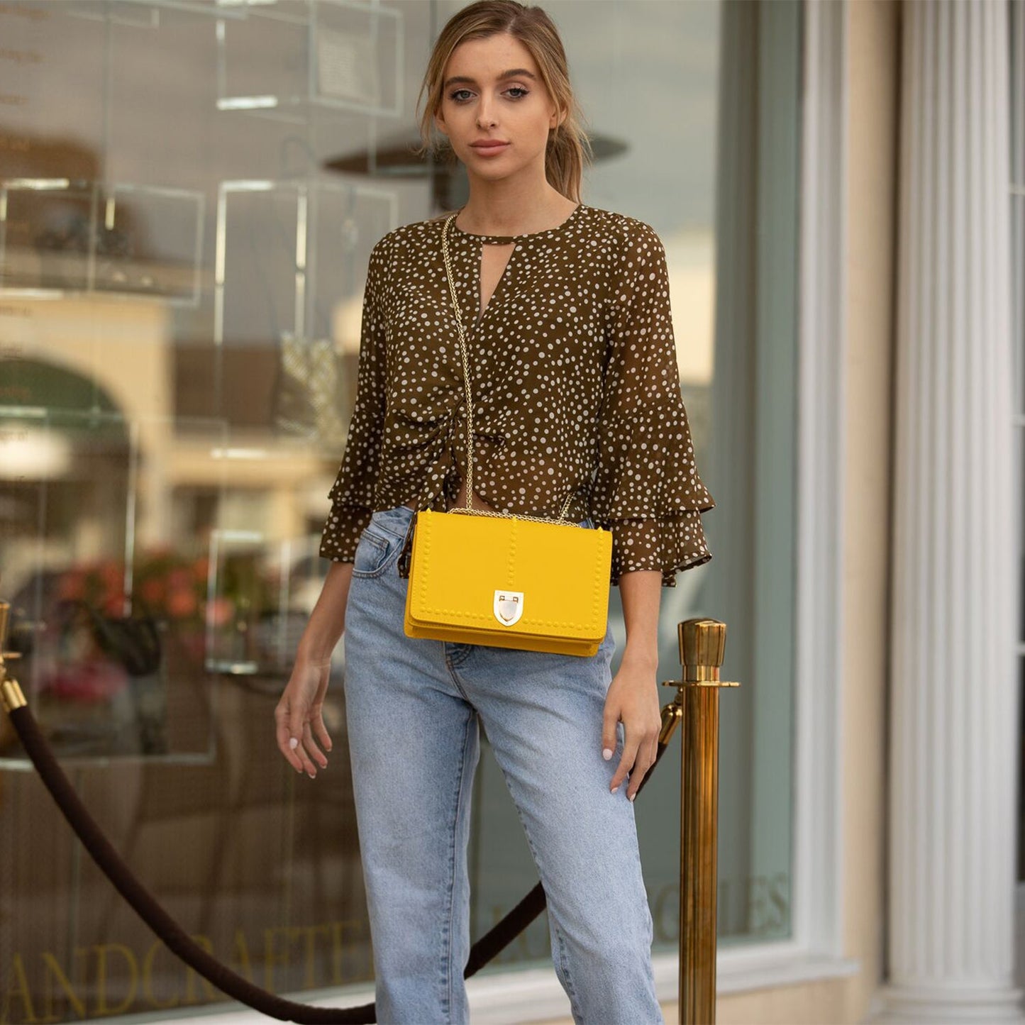 The SUSU Josie Mustard Yellow Leather Purse features gold chain straps, a clasp, and a front row of small studs.