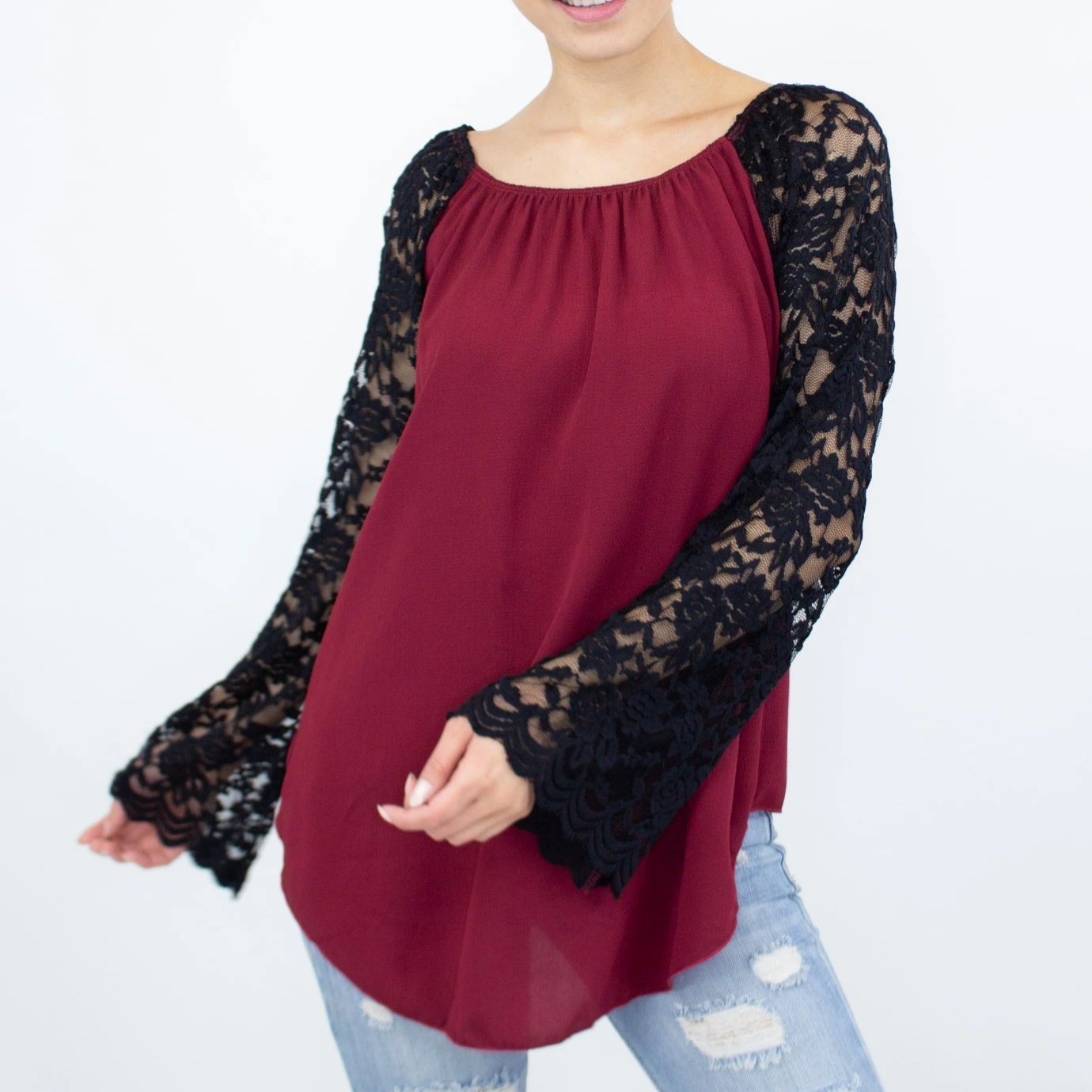 A person wearing a Stylespect Lace Sleeve Backless Top in burgundy and ripped jeans, standing against a plain white background.
