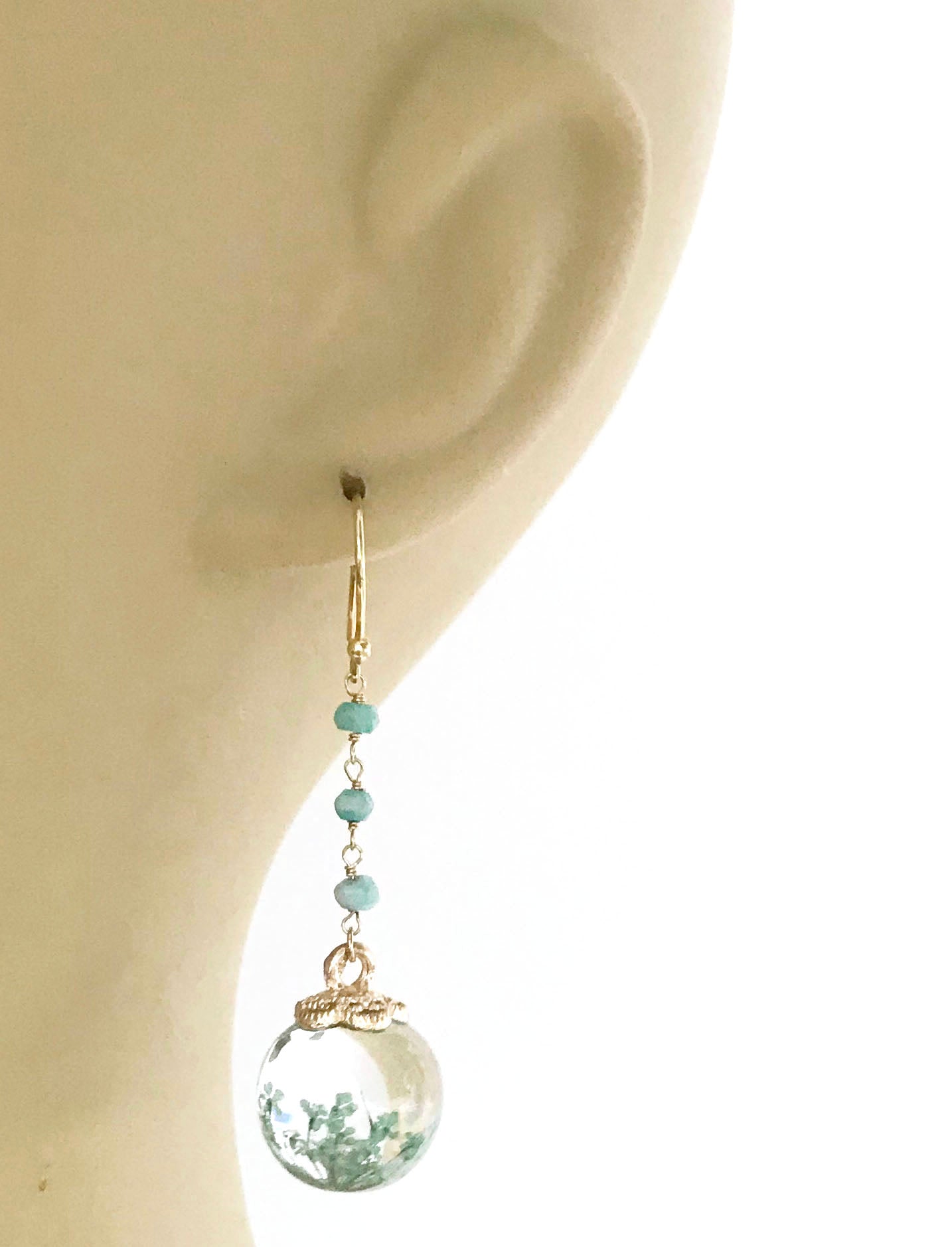 Gena Myints Petrified Flower Keepsake Amazonite Earrings feature dangling earrings with green beads and round spheres showcasing small plant-like designs.