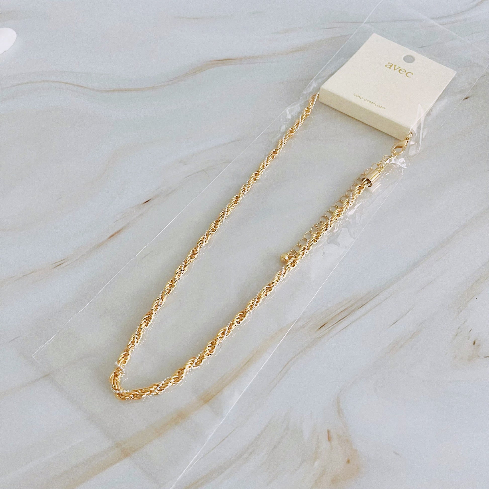 The Fourfect Layered Clip Chain Necklace by Ellison + Young displayed on a white marble surface.
