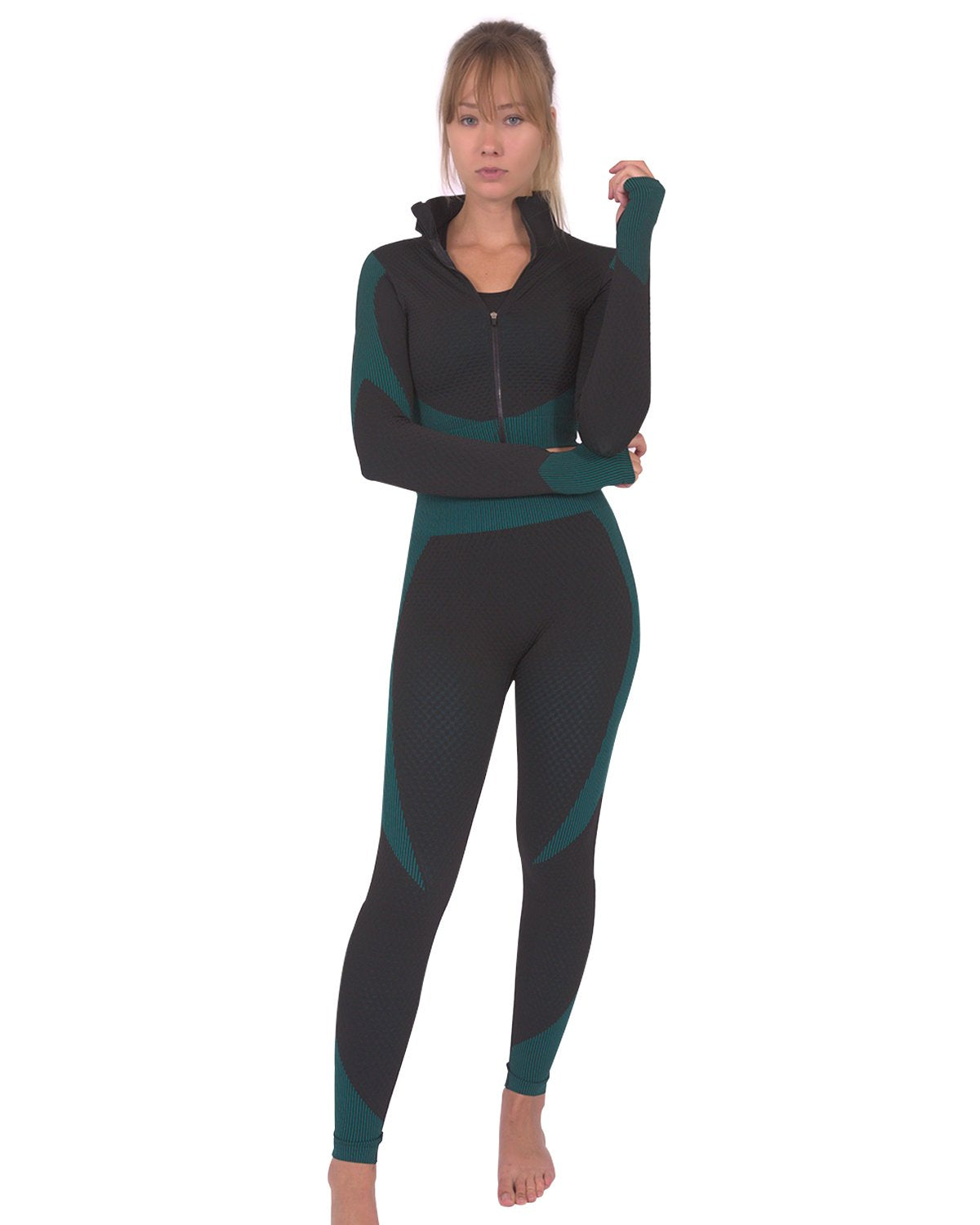 A person wearing Savoy Actives Trois Seamless Legging in Black with Teal Blue and black sneakers stands against a gray textured wall.