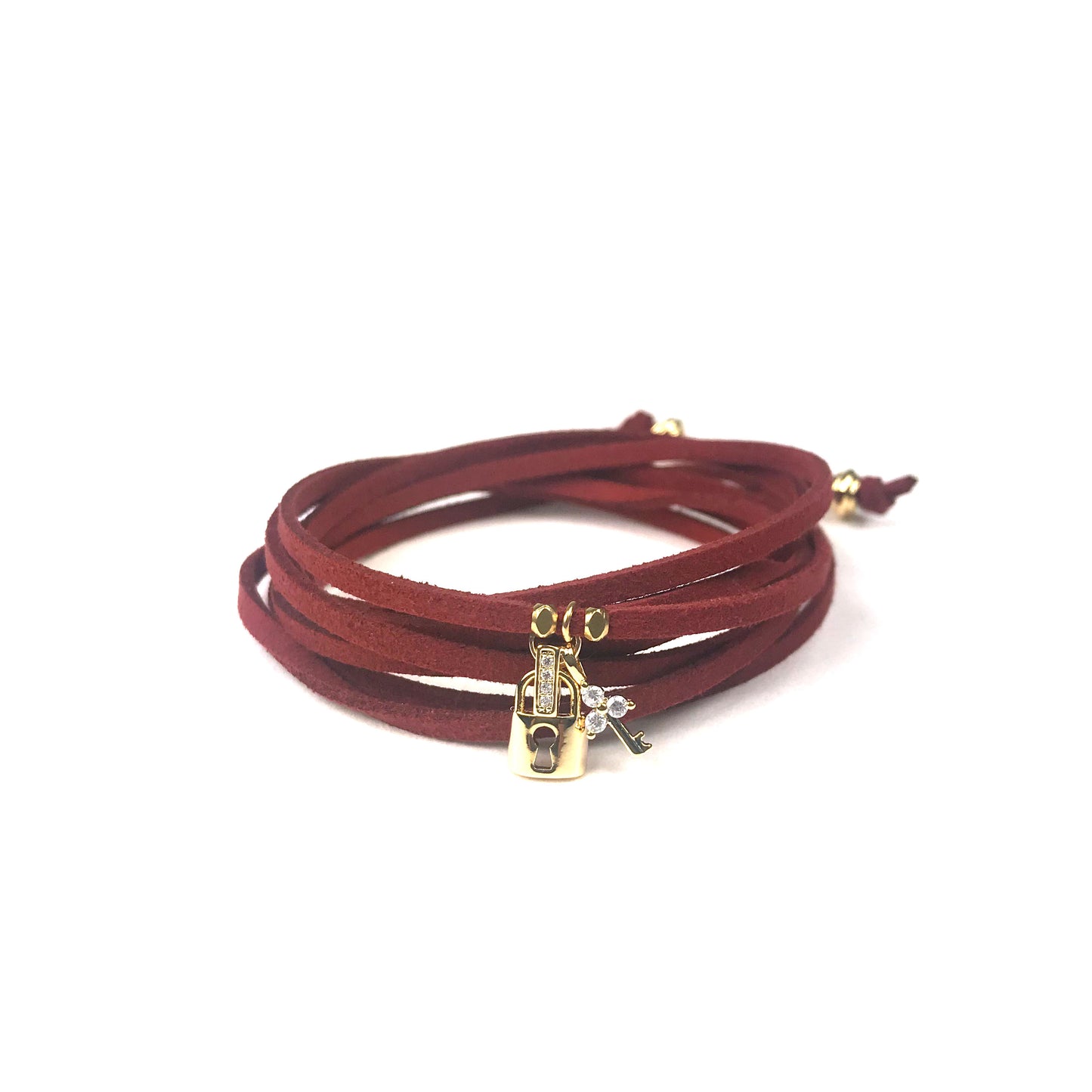 A burgundy suede wrap bracelet by Gena Myint, featuring a gold robot and silver key charm.