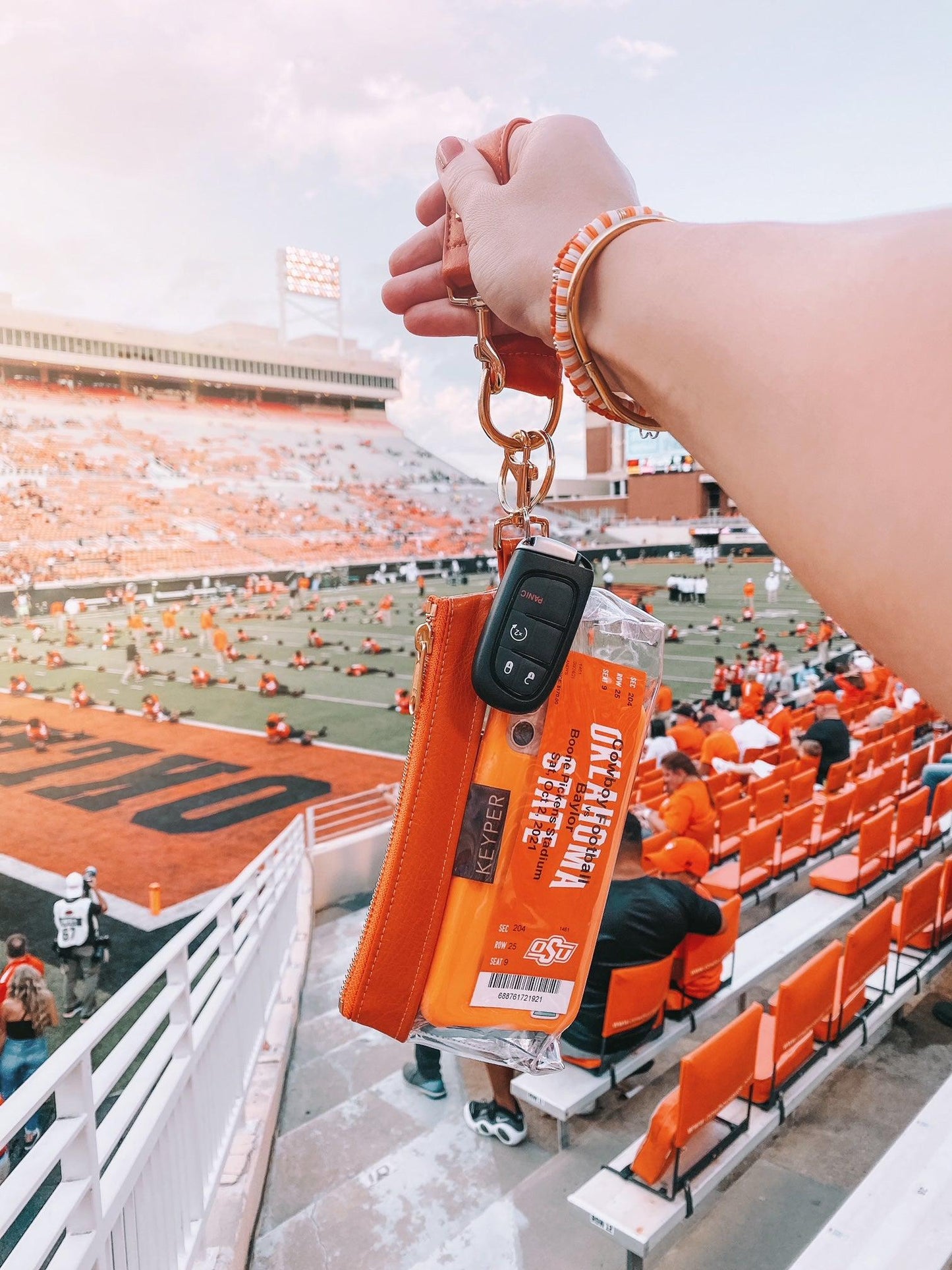 The KEYPER Persimmon Vegan Leather 2-Piece Wristlet Set features a clutch bag with a gold zipper, detachable strap, and small gold keychain.