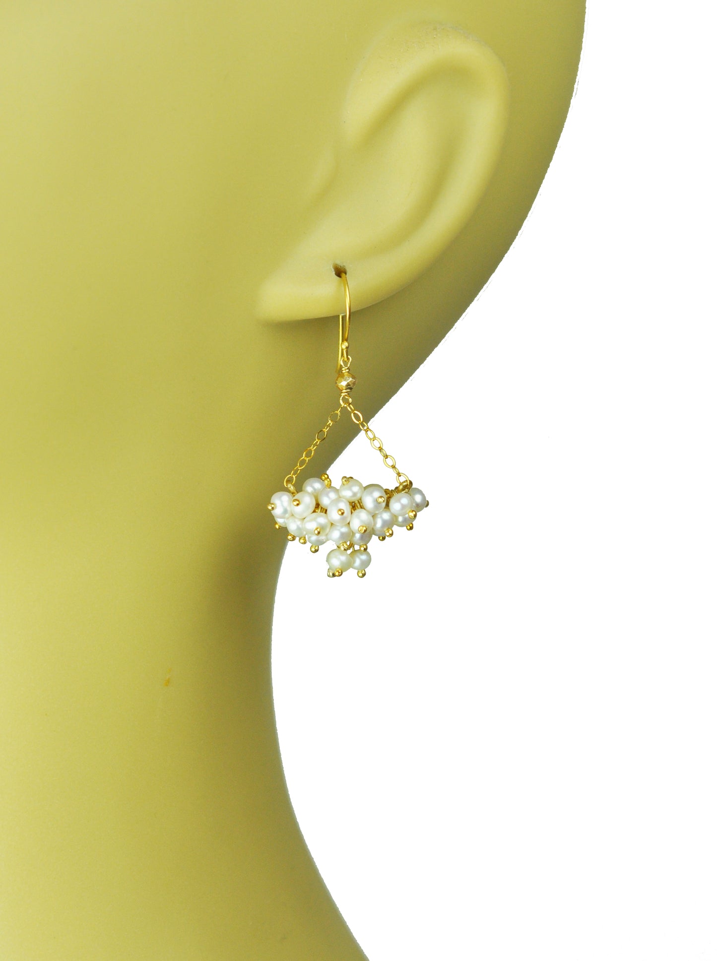 Gena Myints Pearl Cluster Chandelier Earrings feature a pair of gold hooks with white pearls clustered in a pyramid shape.