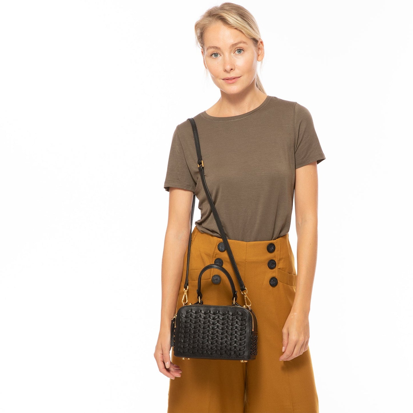 The SUSU Kayla Woven Leather Bag in black features a woven pattern, gold hardware, a top handle, and an adjustable shoulder strap.