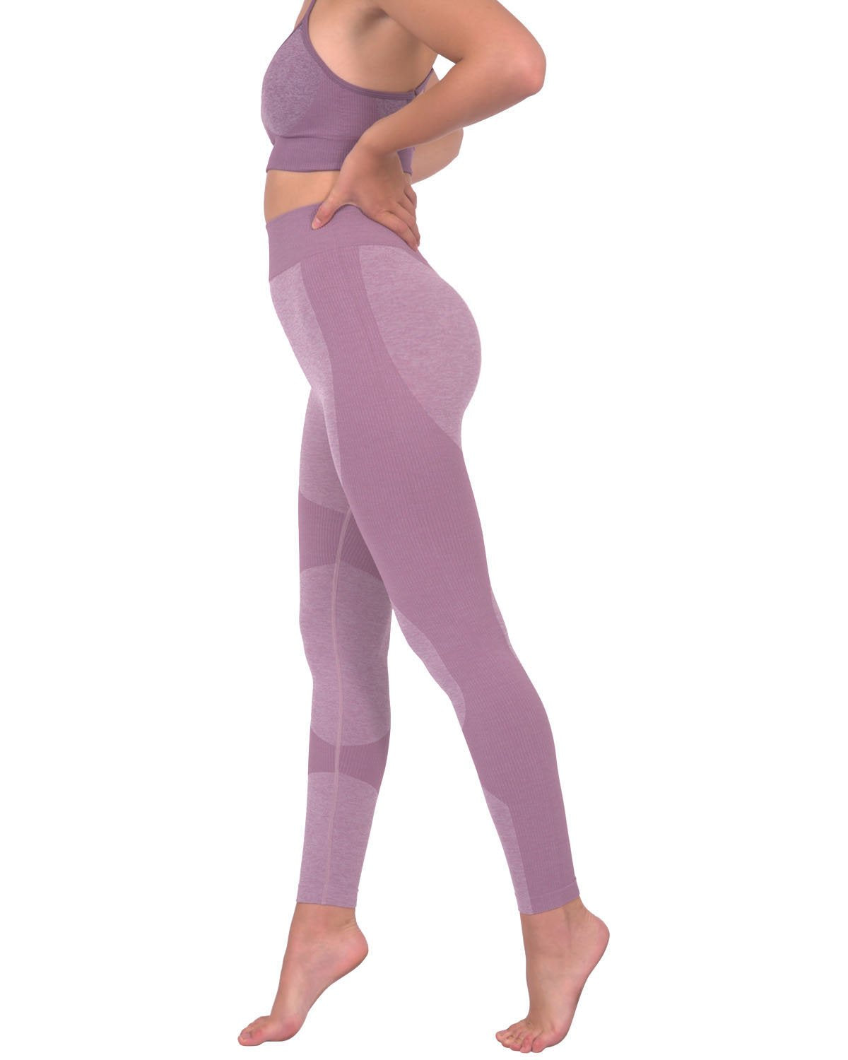 A person in Savoy Actives Megara Seamless Legging With Striped Panels - Purple and black sneakers stands outside a building featuring large glass doors and tropical plants.