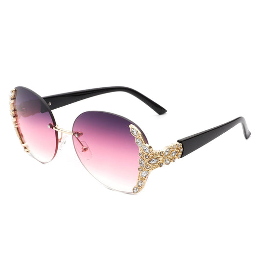 Stylish black sunglasses with oval rimless frames, pink gradient lenses, ornate gold detailing, and rhinestone design by Cramilo Eyewear.