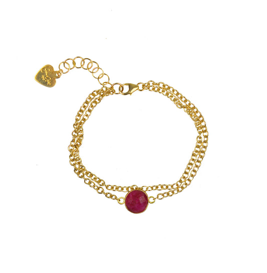 The Gena Myint Ruby Vermeil Double Chain Bracelet features a pink gemstone centerpiece, an adjustable clasp, and a small heart charm.