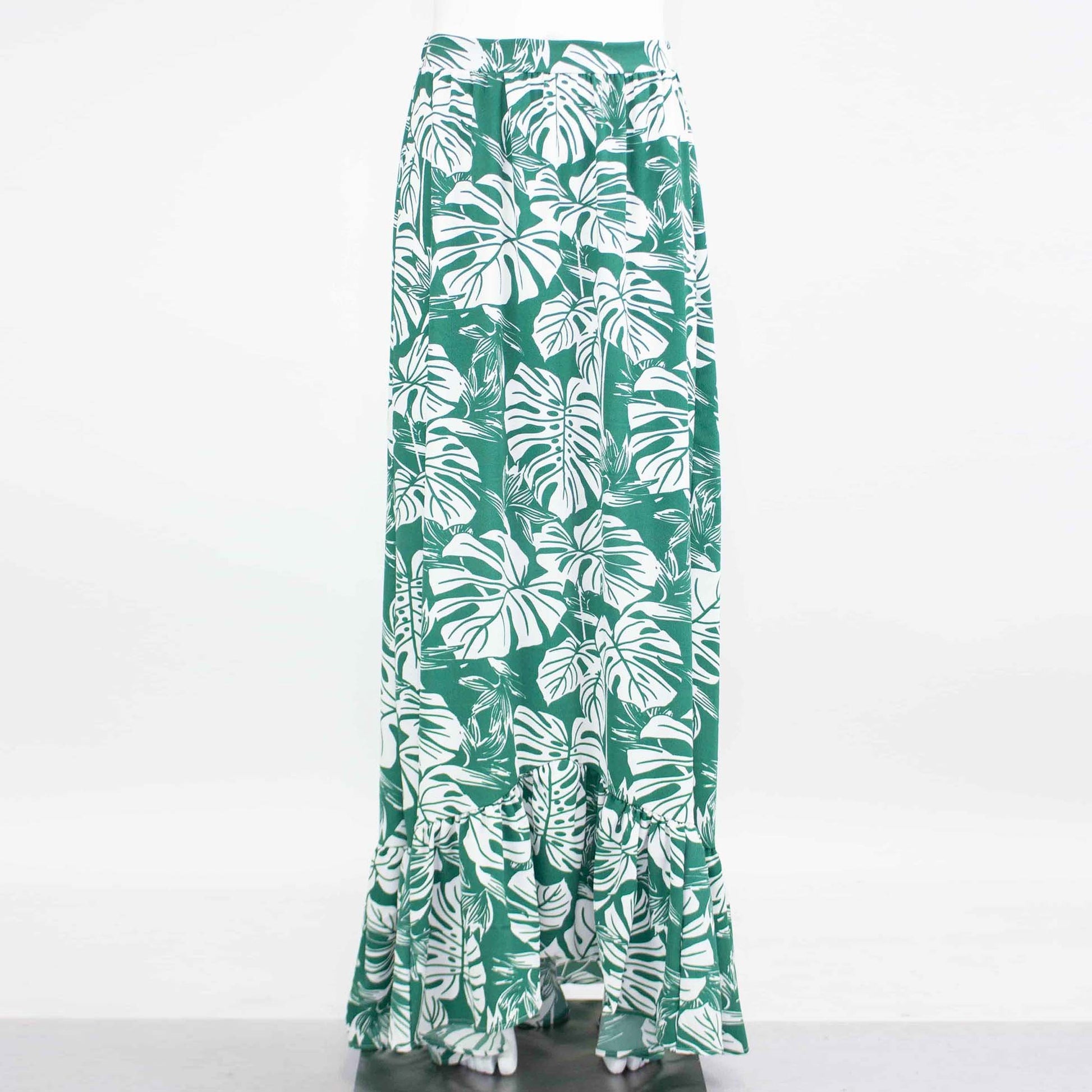 Product: Stylespects Flared Bottom Leaf Maxi Skirt—a long green skirt adorned with a white tropical leaf pattern and ruffled hem.