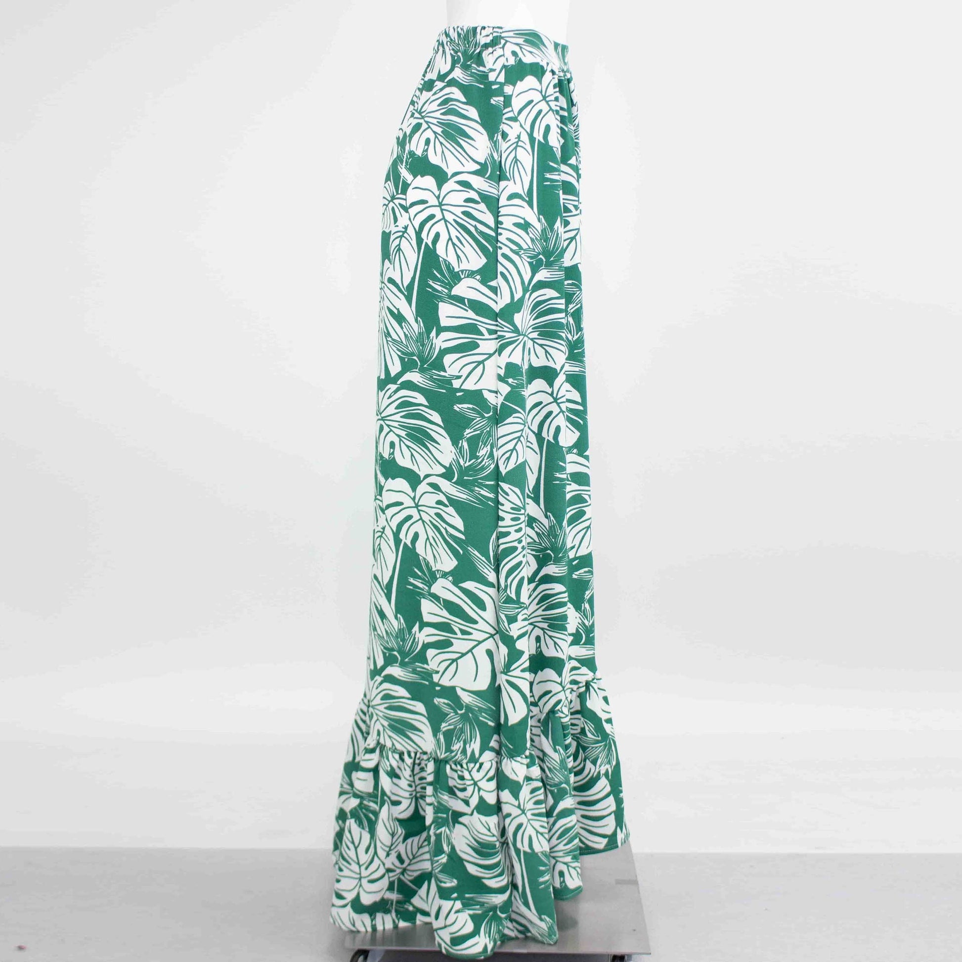 Product: Stylespects Flared Bottom Leaf Maxi Skirt—a long green skirt adorned with a white tropical leaf pattern and ruffled hem.