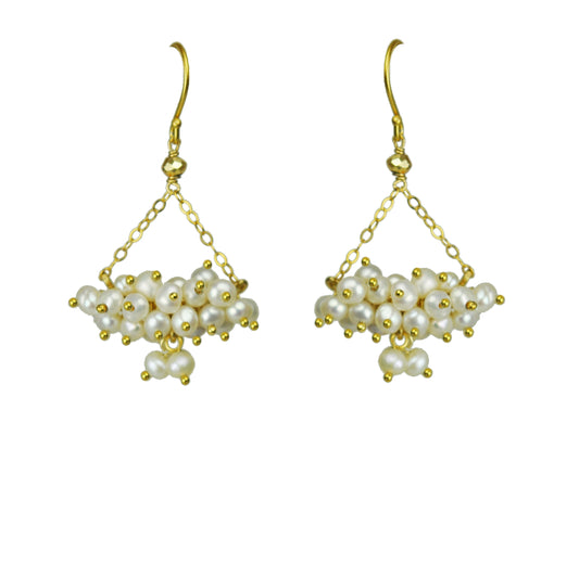 Gena Myints Pearl Cluster Chandelier Earrings feature a pair of gold hooks with white pearls clustered in a pyramid shape.