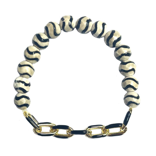 The Wavy Striped Agate Black Enamel Stretch Bracelet by Gena Myint features black and white striped beads with a gold and black chain clasp.