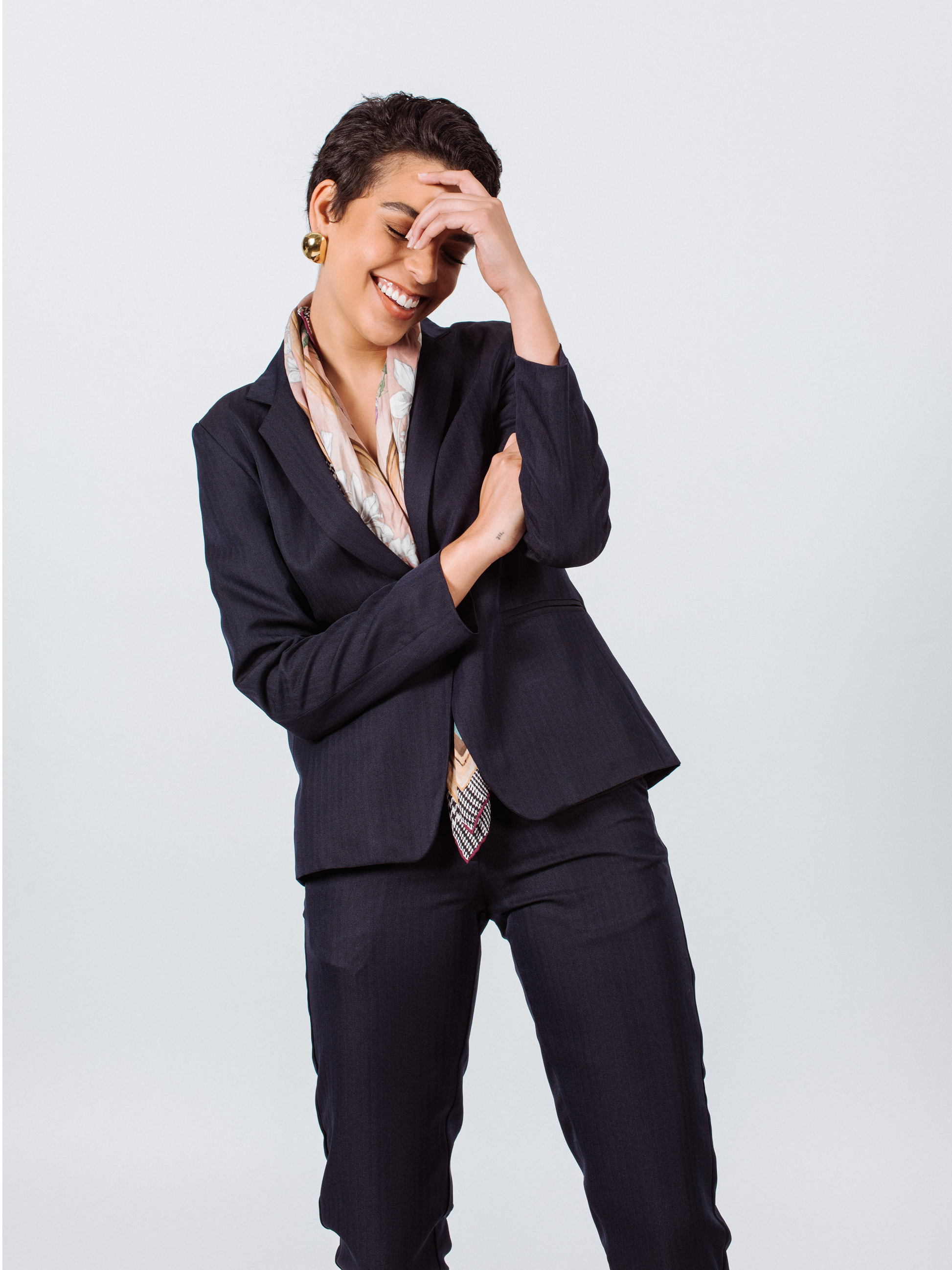 A blonde person stands against a white background wearing a Le Réussi® Navy Peak-Lapels Single-Breasted Blazer and matching pants.